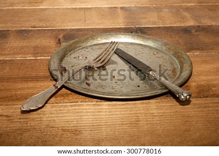 On the table was built, the old tin plate with cutlery and crumbs after eating.