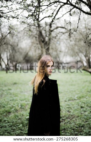 portrait of a beautiful girl in a black coat on the nature