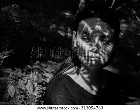 black and white portrait of a beautiful girl in the shade of the leaves