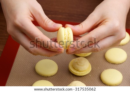 macaroon halves of the connection process in the hands of chef on blurred background