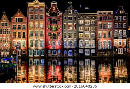 Residential buildings are reflected in the night water. River channel houses in night lights. Night reflection in water. City houses reflected in water in night