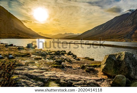 The sun sets over a mountain lake. Mountain lake at sunset. Lake in mountains at sunset. Sunset over lake in mountains