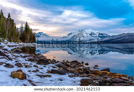 Snow on the shore of a mountain lake. Mountain lake landscape. Snowy mountain lake view. Lake in snowy mountains