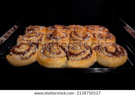 Twelve baked cinnamon buns on tray in electric oven - front view. Swedish cuisine, homemade bakery, food, cooking and pastry concept Сток-фото © 