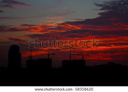 Red clouds seen on the sky above dark silhouette of buildings right after the sunset.