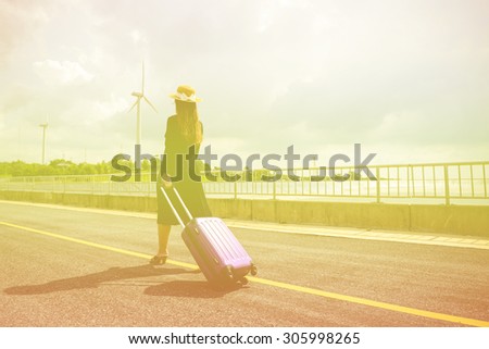 Women dressed in black with purple travel wallet,Traveling by road.