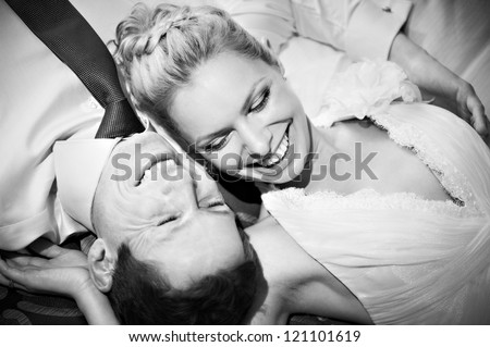 Happy bride and groom lying on bed black and white