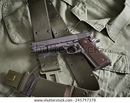Colt gun pistol and belt lie on military jacket closeup
