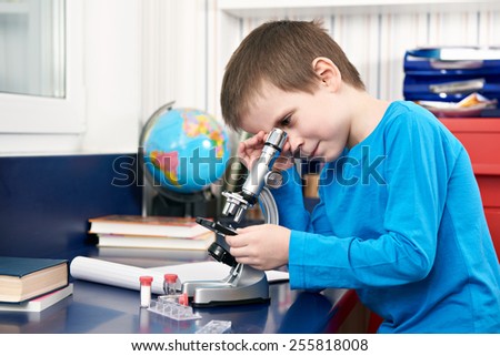 Boy uses a microscope at home learning table