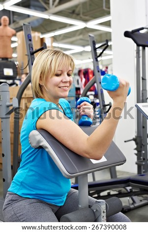 Happy woman tries dumbbell in the sport shop