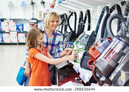 Mother and daughter shopping for electric vacuum cleaner, smiling