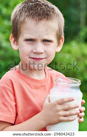 Boy with glass jar of fresh milk in summer day