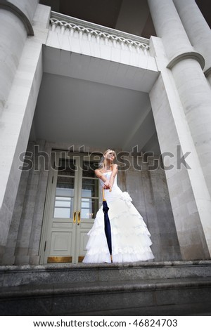 Beautiful Bride with umbrella walking stick at the main entrance of the palace