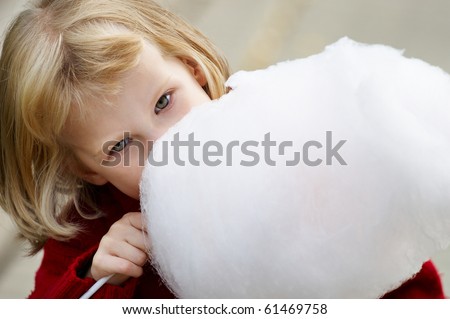 Little girl in a red sweater eating cotton candy