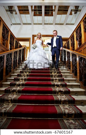 Elegant bride and groom in luxury stairs with red carpet of wedding palace