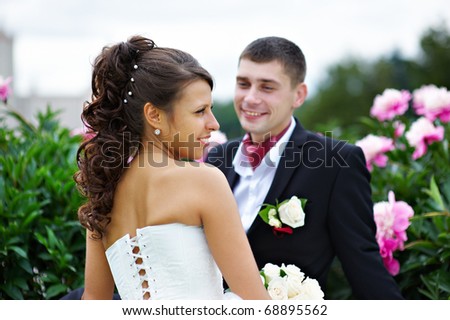 Happy bride and groom at wedding walk in park surrounded by peony flowers