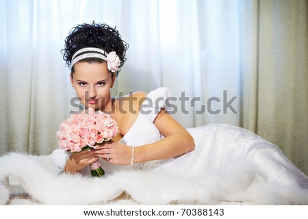 Portrait beautiful bride with bouquet of flowers on white bed in wedding day