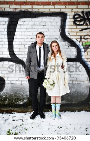 Happy bride and groom against a wall with graffiti on their wedding
