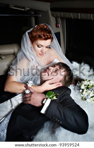 Happy bride and groom into wedding limousine