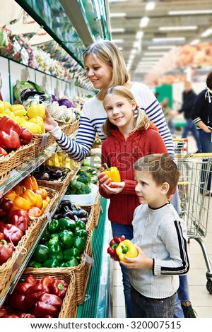 Mother and children with bell pepper in vegetables department in the supermarket