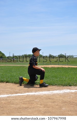 Young Child Kneeling on baseball field wearing Uniform