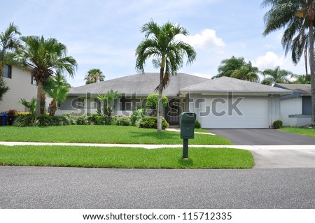 Suburban Ranch Style Home with mailbox on curb in tropical climate residential neighborhood