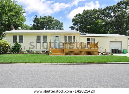 Ranch Style Suburban Home with Wood Deck Trash Cans in front of Garage
