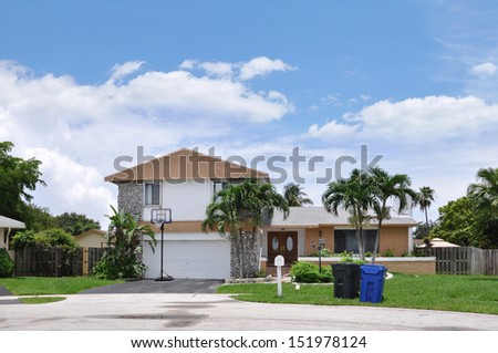 Suburban Back Split Style Home Trash containers front yard lawn blue sky clouds