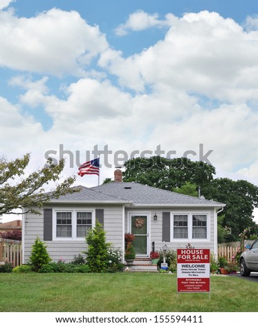 House for Sale Real Estate Welcome Open House Affordable First Time Buyers Sign on front yard lawn of Suburban Bungalow Style Home in residential neighborhood USA American Flag Waving Blue Sky Clouds