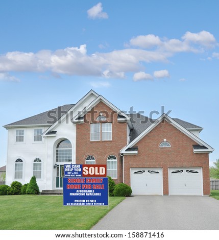 Real Estate Sold Sign Large McMansion Style Brick Home Double Garage Landscaped Front yard Lawn Blue Sky Clouds Residential Neighborhood USA