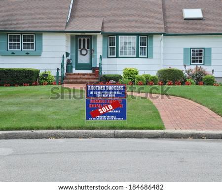 Sold Real Estate sign (another success let us help you buy sell your next home) Close Up of Suburban Home House Front Landscaped Brick Walkway Curb Residential neighborhood USA