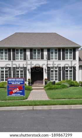 Real Estate Sold (Another success let us help you buy sell your next home) sign Suburban McMansion style home residential neighborhood USA blue sky clouds
