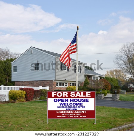 American flag real estate for sale open house welcome sign on lawn of suburban high ranch style home autumn season residential neighborhood blue sky clouds USA