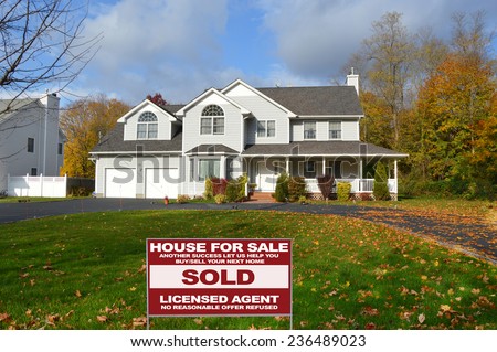 Real Estate sold (another success let us help you buy sell your next home) sign suburban McMansion home autumn day residential neighborhood USA blue sky clouds