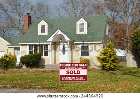Real Estate sold ( another success let us help you buy sell your next home) sign Suburban Cape Cod style home autumn day residential neighborhood USA