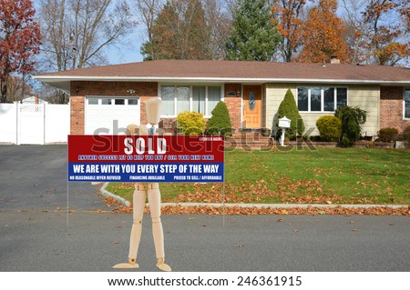 Real estate sold (another success let us help you buy sell your next home) sign suburban brick ranch style home white picket fence blacktop driveway autumn blue sky day residential neighborhood USA
