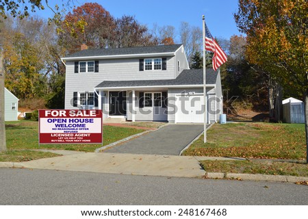 American flag pole Real estate for sale open house welcome sign Suburban Gray High Ranch home autumn day residential neighborhood clear blue sky day USA