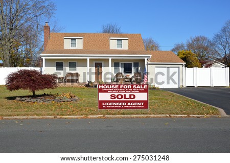 Real estate sold (another success let us help you buy sell your next home) sign Beautiful Cape Cod style home autumn day clear blue sky residential neighborhood USA