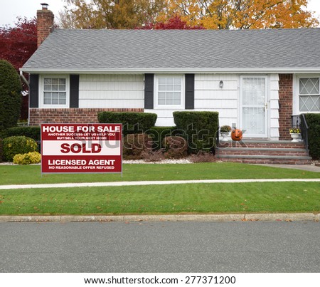 Real estate sold (another success let us help you buy sell your next home) sign Close up of Ranch style Home Autumn Day Residential Neighborhood USA