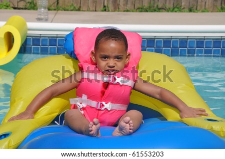 African American Latin Biracial Toddler  Sitting in Family Swimming Pool wearing Pink Life Jacket