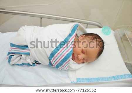 Sleeping Cute Newborn Infant Wrapped in Baby Blanket in Acrylic Hospital Bassinet just after Birth
