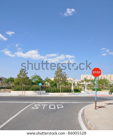 Red Traffic Stop Sign on Empty Street of Urban City Neighborhood Area on Sunny Blue Cloud Sky Day