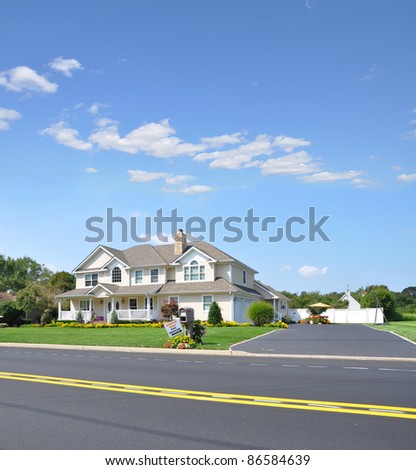 Large Luxury Two Car Garage Suburban McMansion style Home in Residential Neighborhood with Garage Sale Sign next to Mailbox on Sunny Blue Sky Day