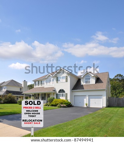 Sold Real Estate Sign on Front Yard Lawn of Landscaped Suburban Home in Residential Neighborhood Sunny Blue Sky Day