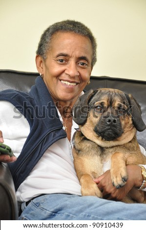 Smiling Happy Mature Woman with Gray short Afro Hairstyle holding pet dog Looking at Camera