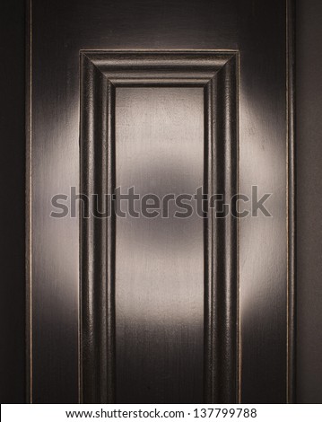Old fashioned interior shutter door, with deep black milk paint, shellac and wax finish, polished to a shiny reflective finish