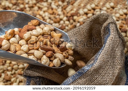 Mixed,roasted nuts on black background with metal nuts shovel, Seller girl's hand seing that holding metal nuts shovel on nuts