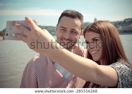 The young man and the attractive woman take a selfie next to the Danube