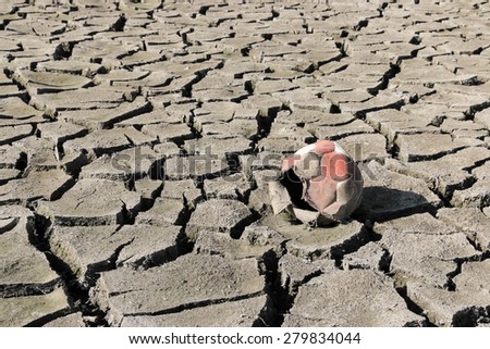 Dry cracked earth and old torn soccer ball