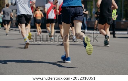 Feet of athletes running marathon in city, onlookers on roadside. Partial view from behind of contestants of sports event. Healthy lifestyle. Concept of sport Stock fotó © 